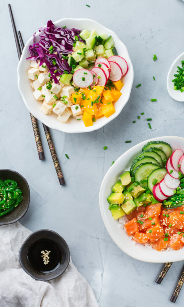 Fast and healthy food, lunch, nutrition concept. Fresh organic hawaiian salmon and tofu poke bowl with rice, seaweed, avocado, cucumber, mango on a modern kitchen table. Top view flat lay background